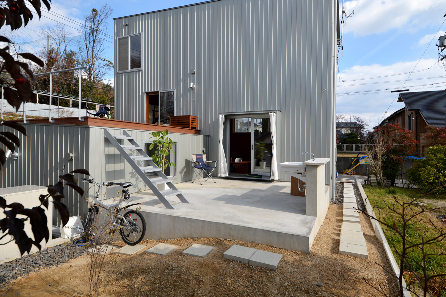 建物南面の外観風景。手前のフリースペースから平屋部分の屋根上に登れる階段が設置されている。