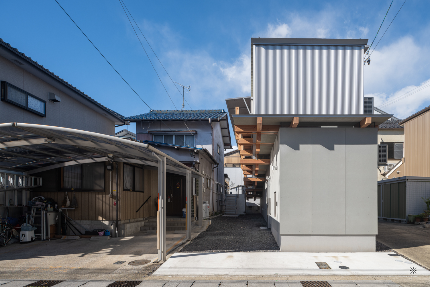 建物の東正面外観風景。グレーの外壁で敷地内の地面には砂利が敷かれている。